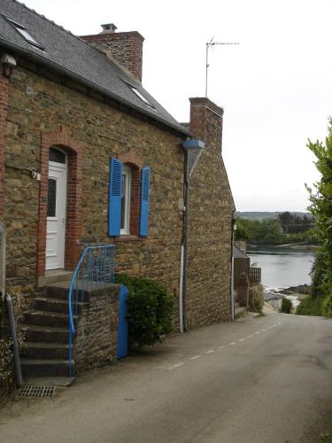 une maison en briques avec des volets bleus et une porte dans l'établissement Le gite de la plage, à Lézardrieux