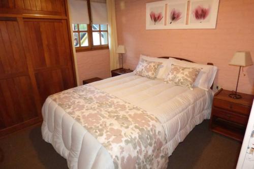 um quarto com uma grande cama branca num quarto em Confortable cabaña en zona céntrica de la ciudad. em San Martín de los Andes