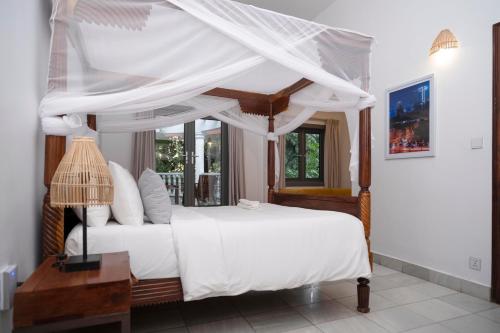 a bedroom with a canopy bed with white sheets at Jungle Addition in Phnom Penh