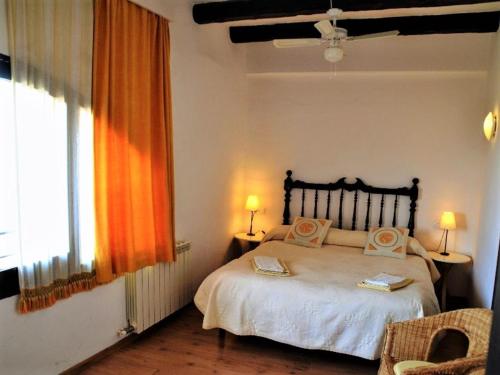 Cal Valeri في Montsonis: غرفة نوم مع سرير ونافذة مع ستائر برتقالية