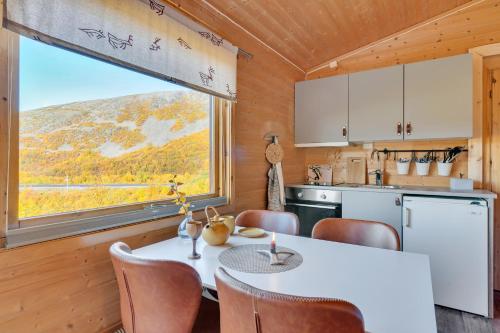 cocina con mesa, sillas y ventana en Davvi Siida - Reindeer Design Lodge en Kjøllefjord