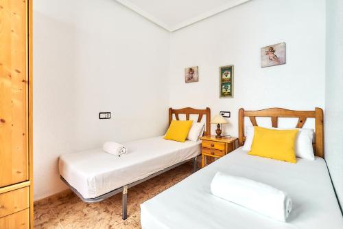 two beds in a small room with yellow pillows at Espanhouse David 2 bedroom apartment Torrevieja with pool in Torrevieja