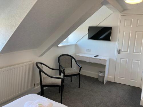 a room with a desk with two chairs and a tv at Norfolk Hotel in Weymouth
