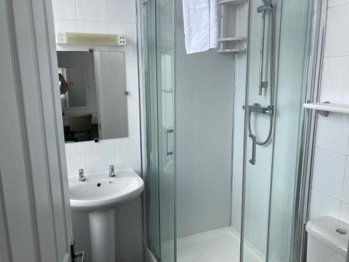 a bathroom with a glass shower and a sink at Norfolk Hotel in Weymouth
