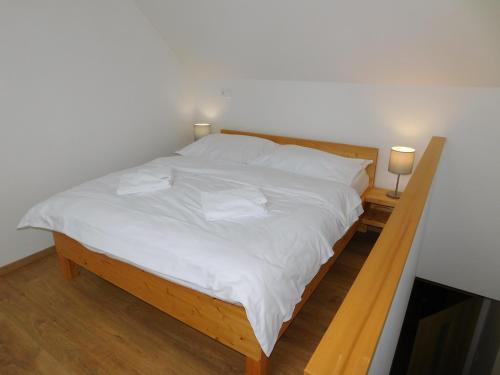 a bed with white sheets and two pillows on it at Penzion Eden in Pec pod Sněžkou