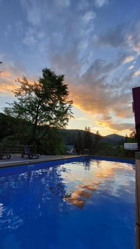 a blue swimming pool with a sunset in the background at Pigy in Tatariv