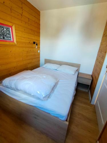un grand lit dans une chambre aux murs en bois dans l'établissement Risoul Appartement 2 chambres Piscine Balcons de Sirius, à Risoul