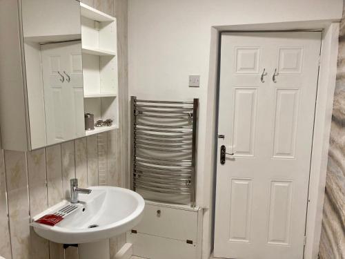 a bathroom with a sink and a white door at A wave from it all in Blackpool