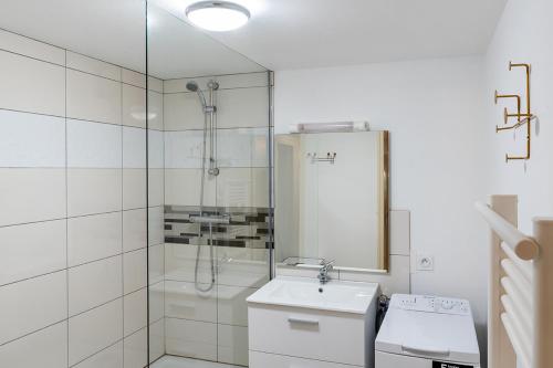 een witte badkamer met een douche en een wastafel bij Logis face à l'Abbatiale in Beaulieu-sur-Dordogne