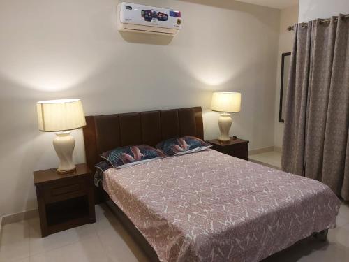 ein Schlafzimmer mit einem Bett und zwei Lampen an Tischen in der Unterkunft The River View Apartment in Rawalpindi