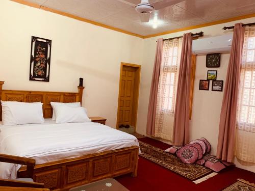 a bedroom with a large white bed and two windows at Bottleneck Lodges in Gilgit