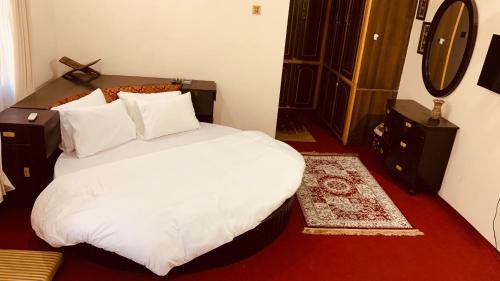 a bedroom with a bed with white sheets and pillows at Bottleneck Lodges in Gilgit