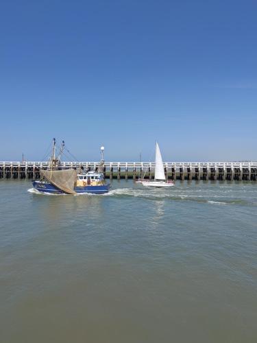 two boats in the water next to a pier at Studio Havenzicht in Nieuwpoort