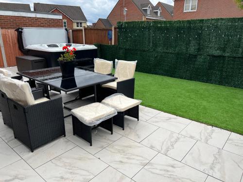 a patio with a table and chairs and a lawn at Luxury 4 bedroom Retreat; with hot tub & parking in Birmingham