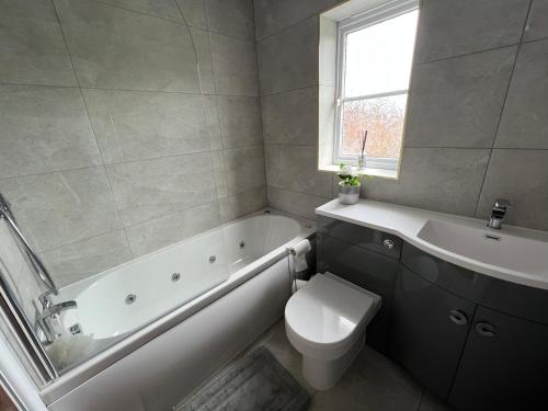 a bathroom with a tub and a toilet and a sink at Luxury 4 bedroom Retreat; with hot tub & parking in Birmingham