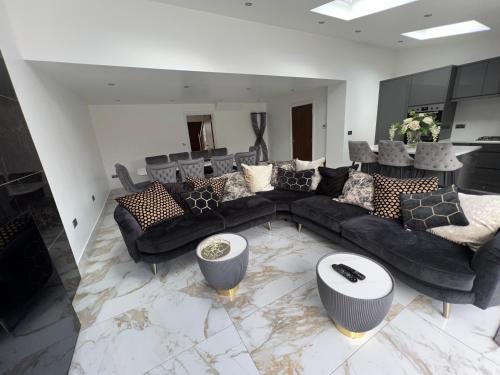 a living room with a black couch and a table at Luxury 4 bedroom Retreat; with hot tub & parking in Birmingham