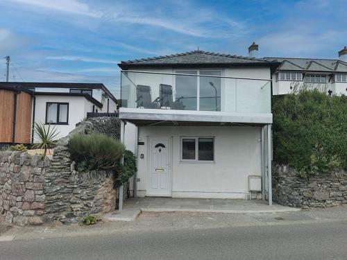 a white house with a white door and a stone wall at LITTLE SUMMER HILL -2 Bed COSY COTTAGE- TREARDDUR in Trearddur