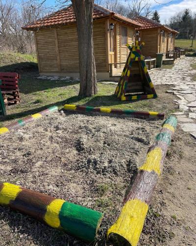 a playground with multicolored painted poles next to a tree at Brvnare Rodjak sa sela in Mionica