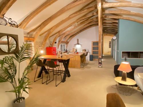 a large room with wooden ceilings and a table and chairs at Cahors - Lot - Les Lumières du Causse - Domaine en pierres blanches avec vue sur les causses in Bellefont-La Rauze