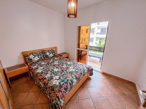 1 dormitorio con 1 cama con colcha de flores y ventana en Visit Oued Laou - Jawhara, en Oued Laou