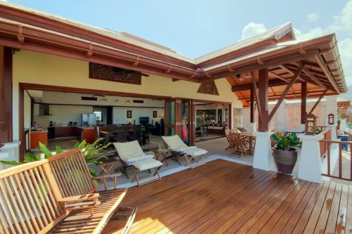 una terraza de madera con sillas y mesas. en Patong Seaview Luxury Villa Penda, en Patong Beach