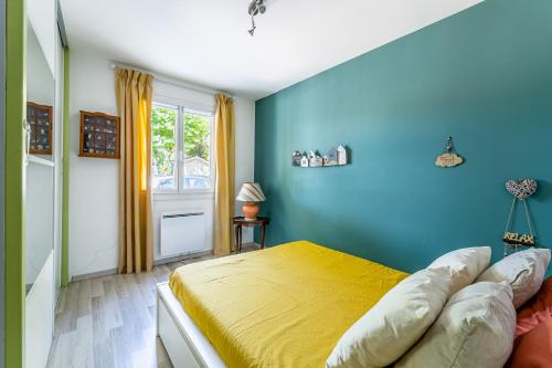 a bedroom with a yellow bed and a blue wall at Le Nadadou par Dodo à Cassis in Cassis