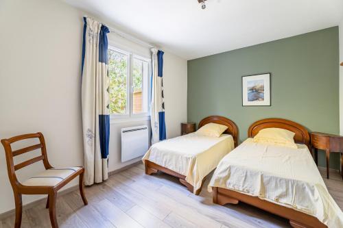 two beds in a room with a chair and a window at Le Nadadou par Dodo à Cassis in Cassis
