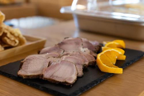 a piece of meat and orange slices on a black plate at Armantanis Luxury Suites in Areopolis