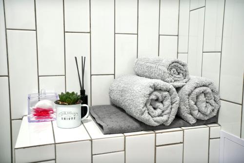 a white tiled bathroom with towels on a shelf at Almaty Aparts in Almaty