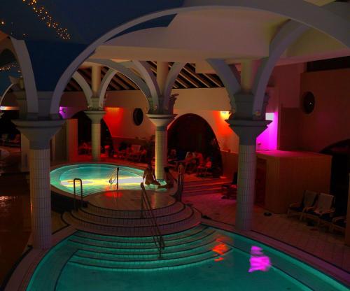 a swimming pool in a building with a restaurant at Aquatherma Termálfalu Zalaegerszeg in Zalaegerszeg