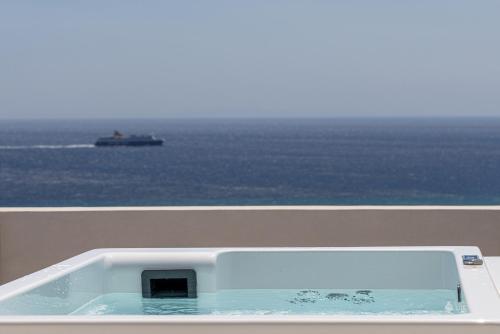 a bath tub on a balcony with a ship in the ocean at Blue Gres Villa Tinos in Tinos Town
