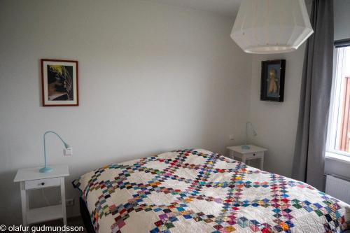 a bedroom with a bed with two lamps on the wall at Comfortable apartment in Vogar