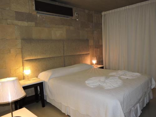 1 dormitorio con 1 cama con sábanas blancas y 2 lámparas en Apart Spa Linda Bay en Mar de las Pampas