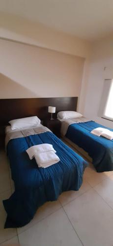 two beds in a hotel room with towels on them at DEPTOS BAHIA in Bahía Blanca