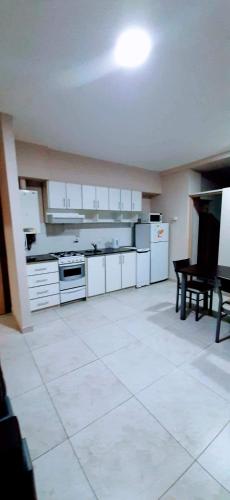 a large kitchen with white cabinets and a table at DEPTOS BAHIA in Bahía Blanca