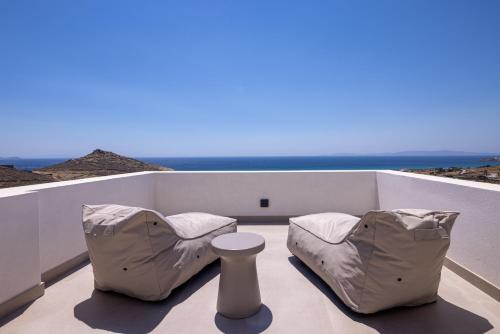 a balcony with two chairs and a table and the ocean at Blue Gres Villa Tinos in Tinos Town