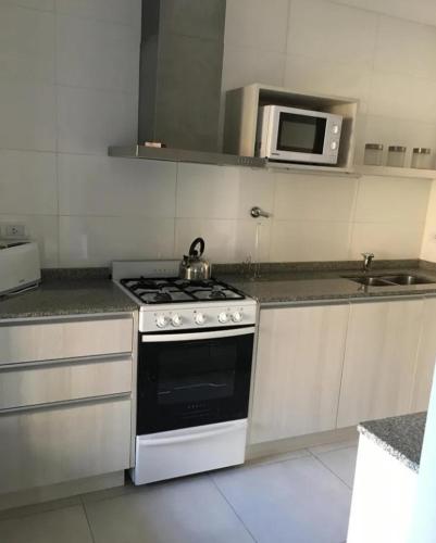 a kitchen with a stove and a microwave at La Barracuda in Pinamar