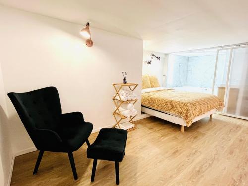 um quarto com uma cama e uma cadeira preta em Duplex-Ceiling height 1,9m-Free private parking-Netflix-Self check in !! Duplex climatisé-Hauteur sous plafond 1,9m-Parking privé gratuit-Netflix-Arrivée autonome !! em Avignon