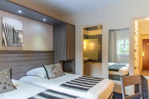 a hotel room with two beds and a kitchen at LOGIS Hôtel & Restaurant - LENSOTEL in Lens