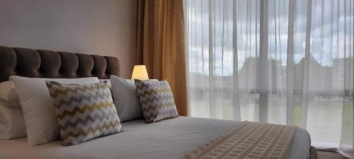 a bedroom with a bed with pillows and a window at Hotel Angelas in Utena
