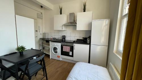 a small kitchen with a table and a refrigerator at Lovely studio flat in the heart of Holloway. in London