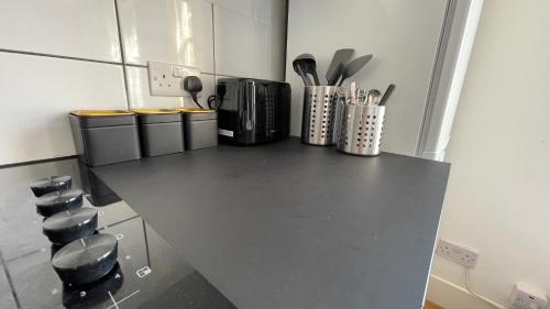 a kitchen with a black counter top with utensils at Lovely studio flat in the heart of Holloway. in London