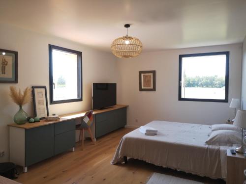 une chambre avec un lit et un bureau et deux fenêtres dans l'établissement Mas Puig Grand Gîte, à Saint-Génis