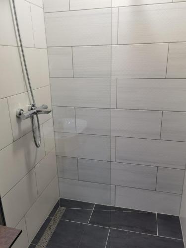 a shower with a white tiled wall at D8 B&B in Zadar