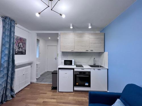 eine Küche mit weißen Geräten und einer blauen Wand in der Unterkunft Superbe appartement 1 bedroom équipée 2P Parc des Princes in Boulogne-Billancourt