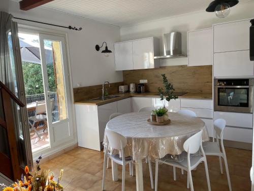 une cuisine avec une table et des chaises et une cuisine avec des armoires blanches dans l'établissement U Pagliaghju, à Santa-Reparata-di-Balagna