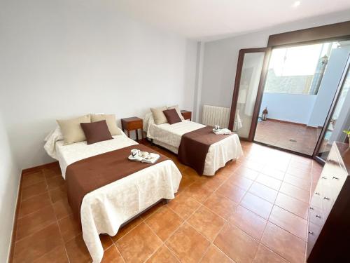 two beds in a room with a tile floor at Casa de la Plaza in Fondón