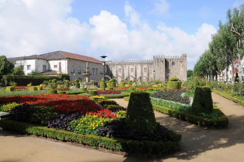 a garden with flowers and a castle in the background at Hotel Sao Nicolau in Braga
