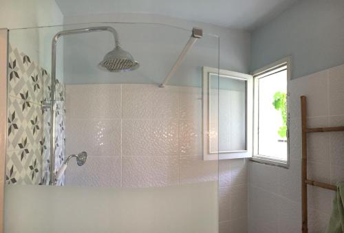 une salle de bain avec une douche avec une porte vitrée dans l'établissement Maison de charme en bord de Mer, au Barcarès