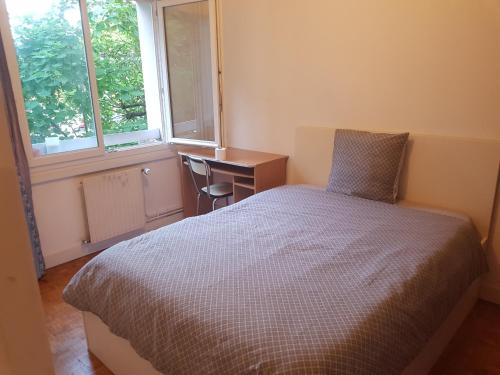 a bedroom with a bed and a desk and a window at une chambre privee entre paris et disneyland in Noisy-le-Grand